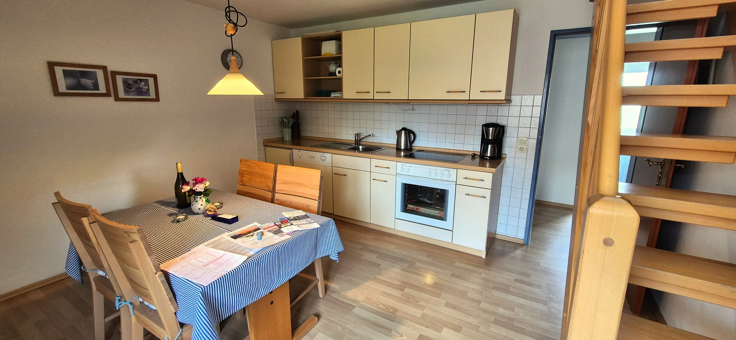 Glockenblume – Offene Wohnküche mit cremefarbener Küchenzeile: Ober- und Unterschränke, Geschirrspüler, Cerankochfeld mit Backofen, …