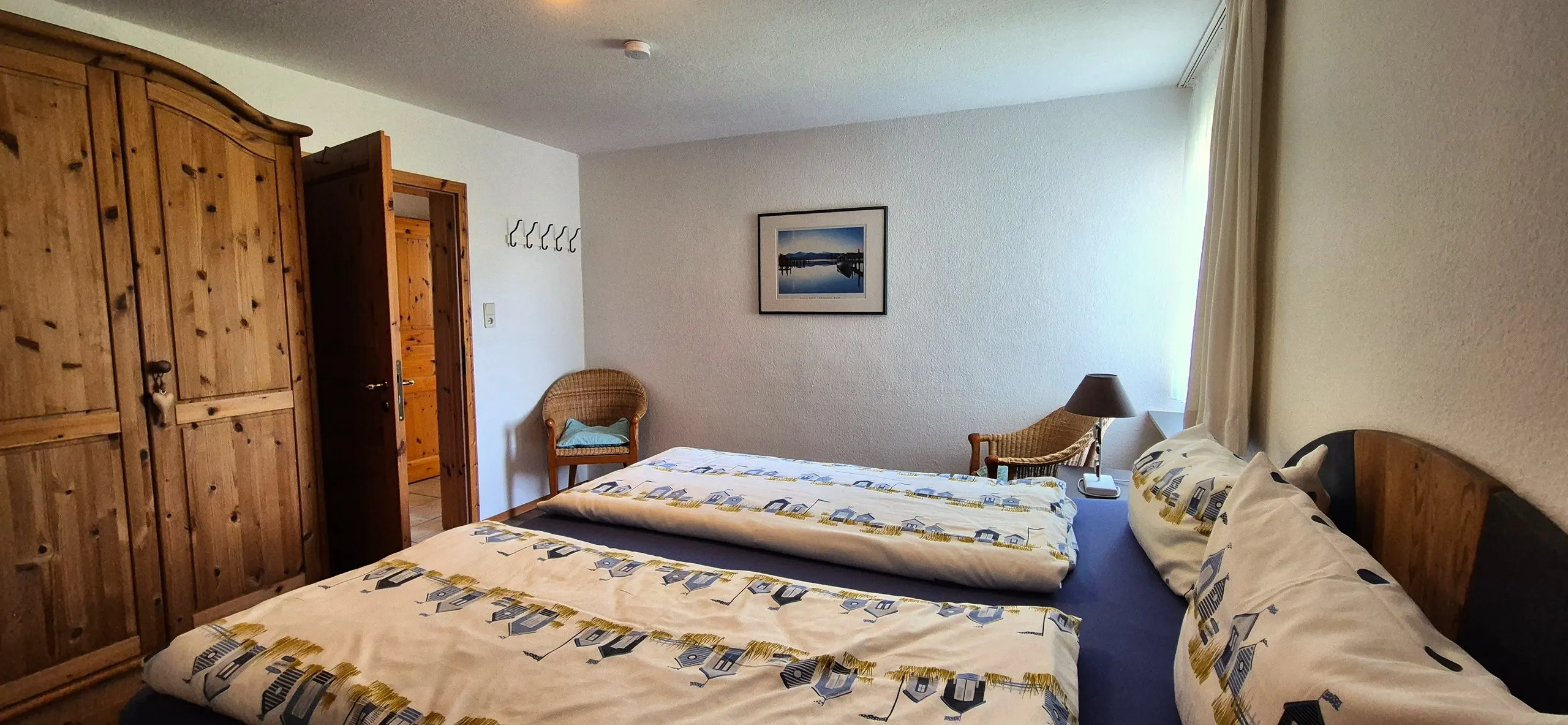 Grasnelke – Geräumiges Schlafzimmer mit massivem Kiefernholz-Kleiderschrank und zwei zusammengeschobenen Betten mit maritimer …