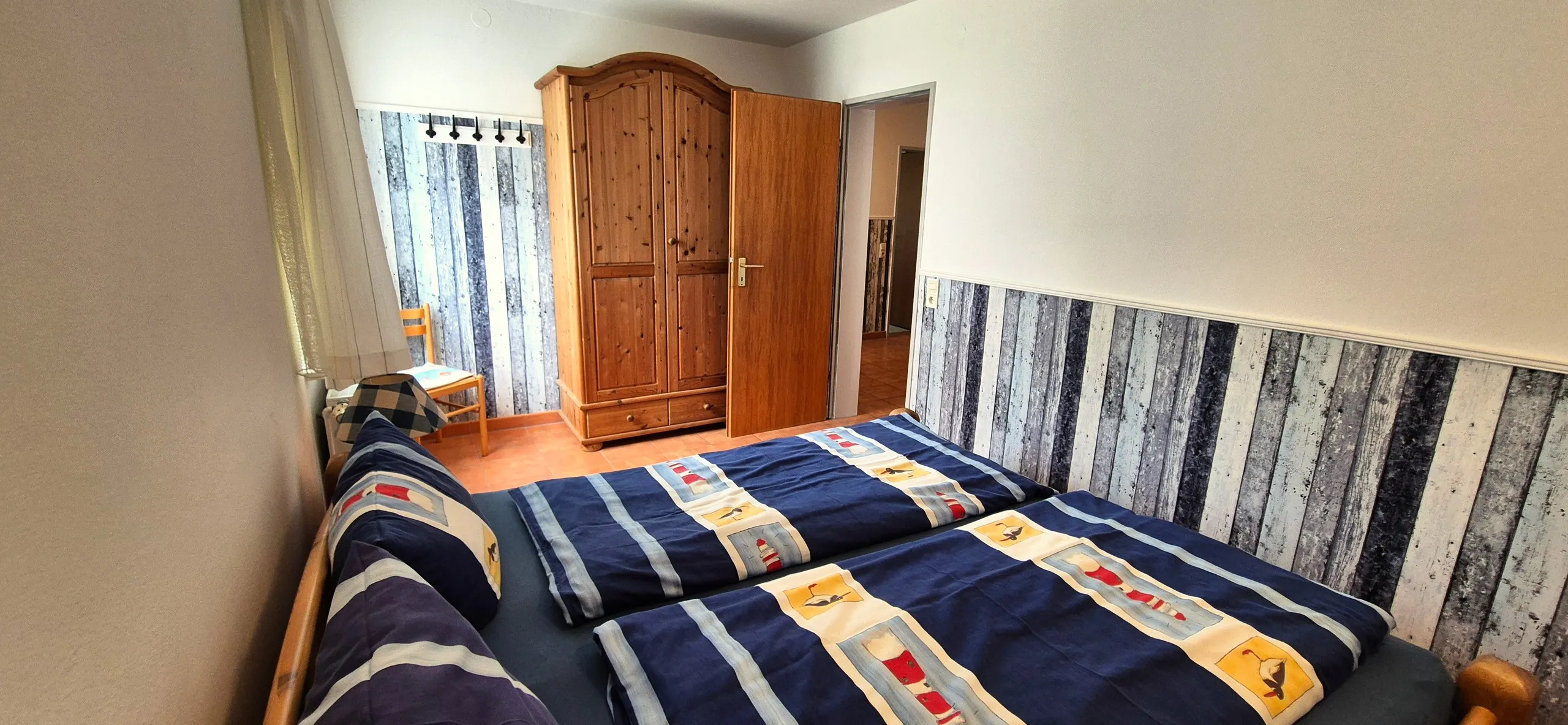 Austernfischer – Gleiches Schlafzimmer wie im vorherigen Bild, diesmal mit Blick auf einen Kiefern-Kleiderschrank und die offene Tür zum …