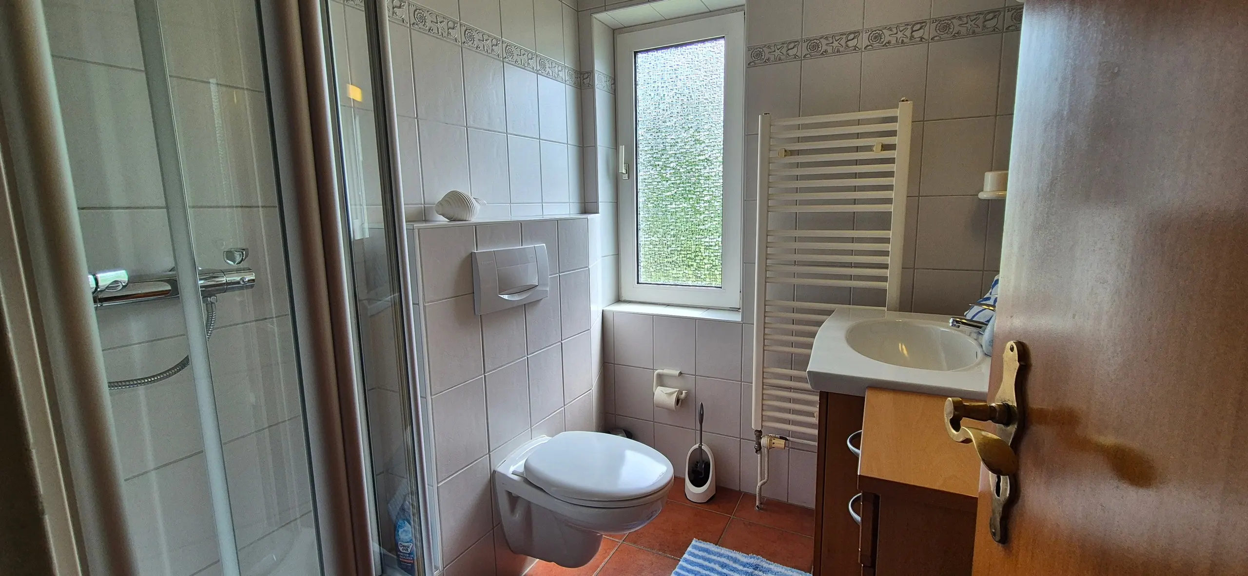 Sonnentau – Kleines Badezimmer mit Eckduschkabine aus Glas, wandhängendem WC und weißem Handtuchheizkörper neben einem …