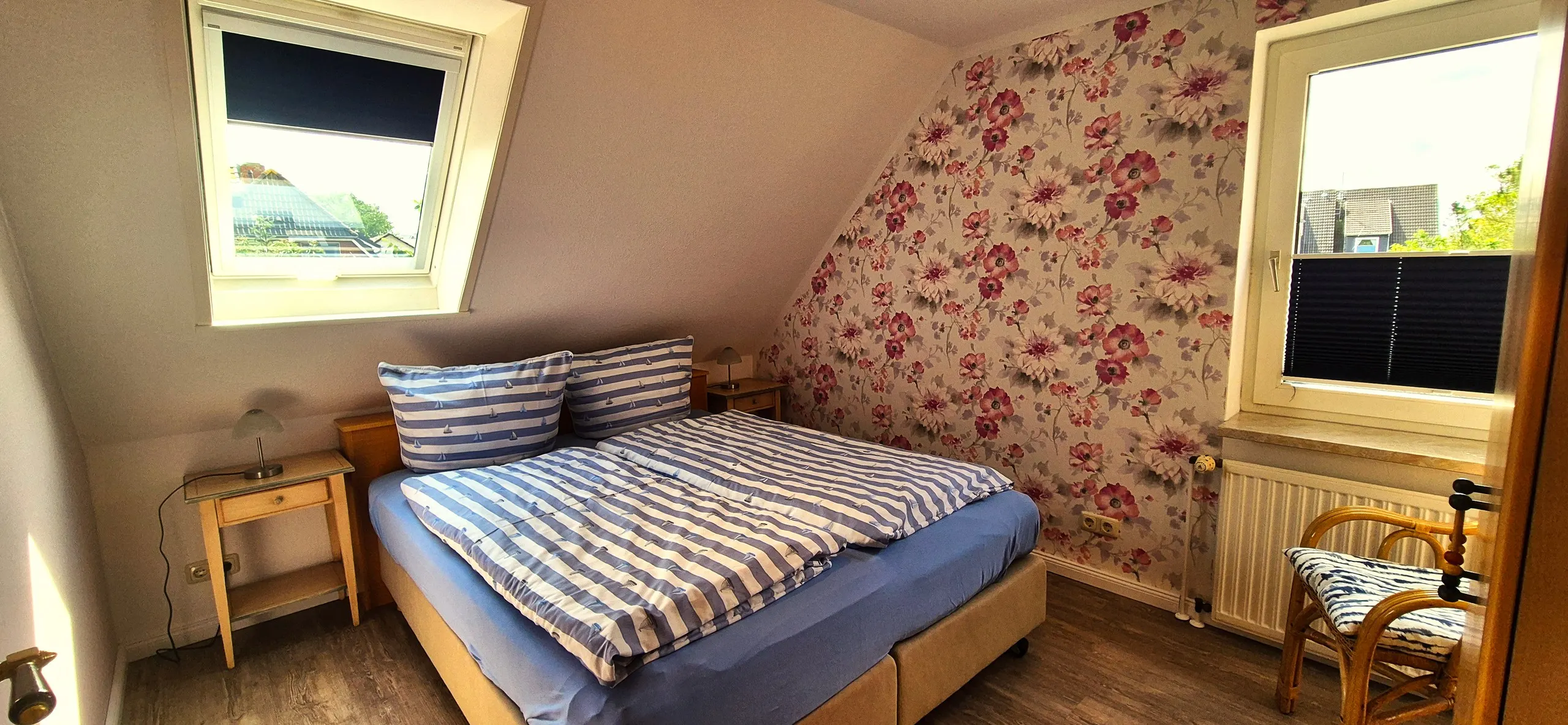 Küstenhaus – Schlafzimmer im Dachgeschoss mit schräger Wand, versehen mit großformatiger rosa-roter Blumentapete als Blickfang …